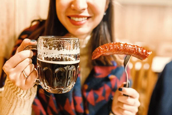 Genç mutlu kadın yiyor Kızarmış sosis ve bira fincan içecekler bar — Stok fotoğraf