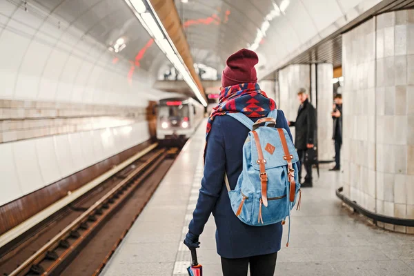 Visão traseira de uma mulher mochileiro esperando a chegada do trem no metrô ou metrô — Fotografia de Stock