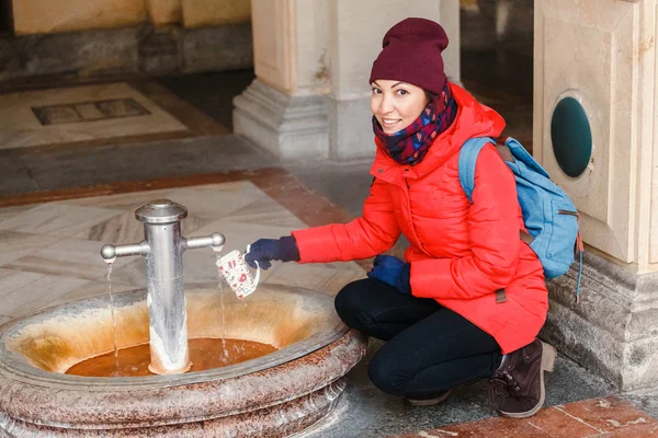 O femeie fericită bea apă dintr-un izvor termic fierbinte în Karlovy Vary, Republica Cehă pe timp de iarnă — Fotografie, imagine de stoc