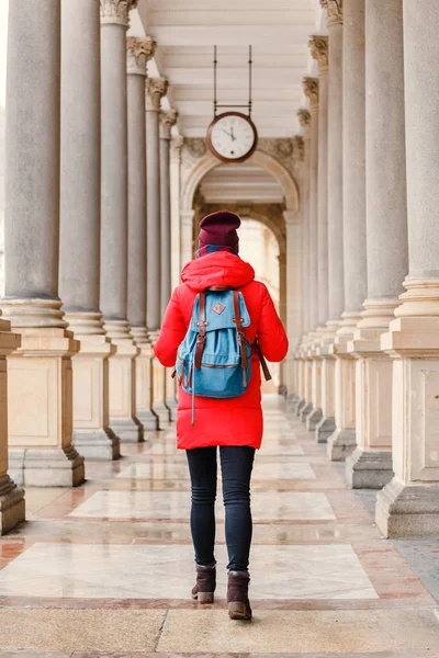 Mladý cestovatel žena s batohem v krásné kolonádě s minerální vodou v resortu Karlovy Vary v České republice v zimním období — Stock fotografie