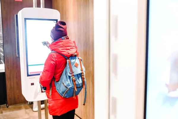 Una mujer pide comida en el terminal de pantalla táctil en el menú electrónico en el restaurante de comida rápida — Foto de Stock