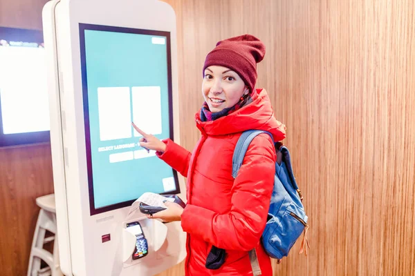 A woman orders meal in the touch screen terminal in the electronic menu in the fast food restaurant — Stock Photo, Image