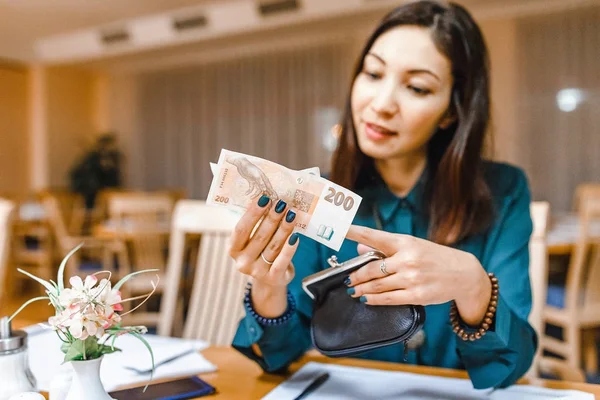 Женщина-клиент в ресторане после ужина получает деньги из кошелька, чтобы оплатить счет — стоковое фото
