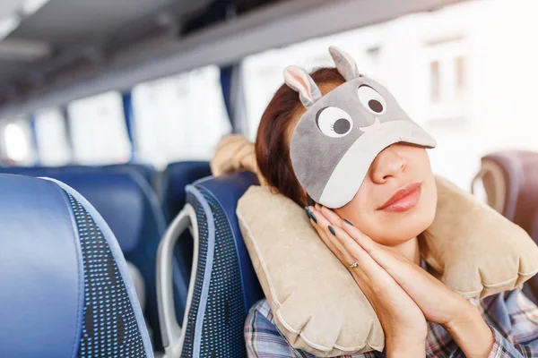 Giovane bella donna che dorme in autobus in maschera divertente e con cuscino — Foto Stock