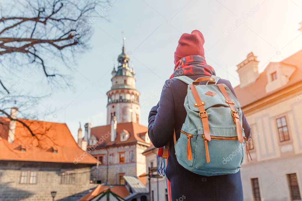 Happy young woman with backpack travelling in Cesky Krumlov at winter