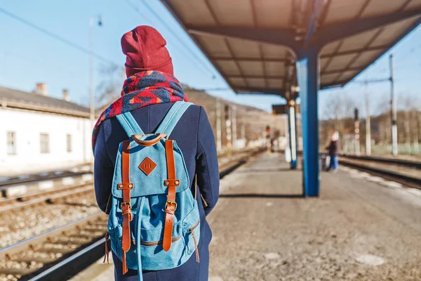 Uma jovem turista com mochila espera trem na estação ferroviária — Fotografia de Stock