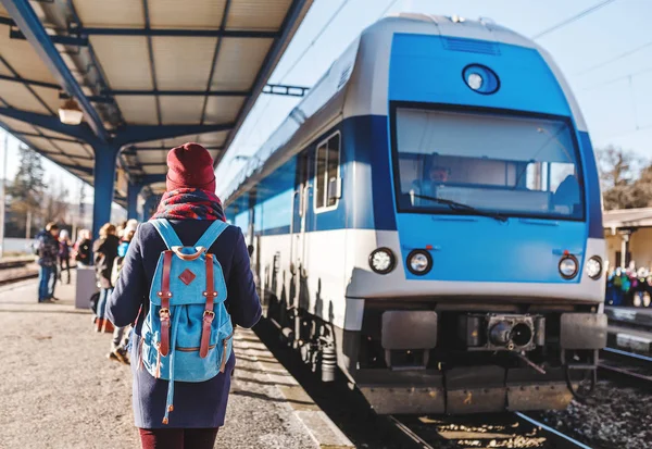 En ung turist flicka med ryggsäck väntar tåget på järnvägsstation — Stockfoto