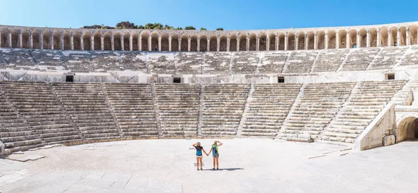 2 つの若い女の子学生旅行者古代ギリシャの円形劇場のツアーをお楽しみください。 — ストック写真