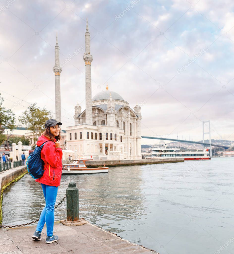 A tourist girl walks near the great sight in Istanbul, the mosque of Ortakoy