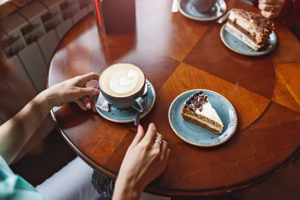 Дві жінки спілкуються в кав'ярні, торт на столі — стокове фото