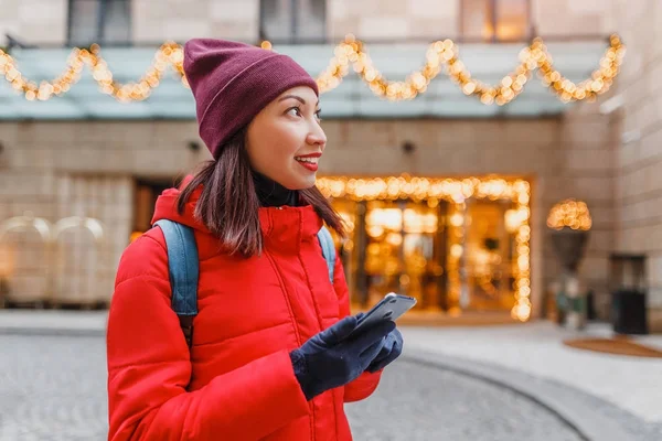 Traveler woman with mobile phone at hotel building at city street