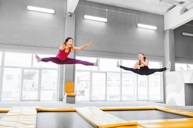 İki genç aktif kadınlara bir modern fitness merkezinde trampolines üzerinde atlama