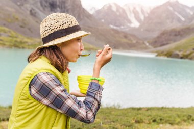 Kadın sıcak çorba dağ gölü yakınındaki bir kase yemek tadını uzun yürüyüşe çıkan kimse