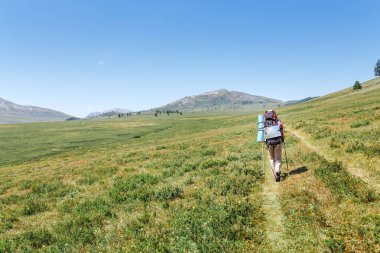 Dağlar, açık hava etkinlikleri ve macera doğa kavramı içinde yalnız patika yol boyunca yürüyüş sırt çantası olan mutlu kadın