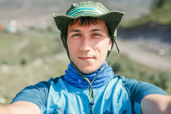 Bonito homem aventureiro de chapéu tirando selfie na caminhada na montanha — Fotografia de Stock