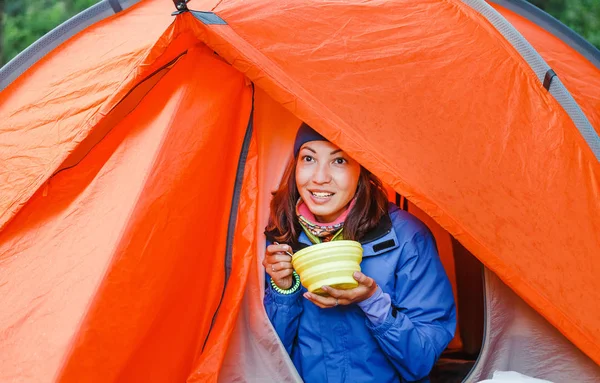 Mulher sorridente turista comer comida quente enquanto acampa na natureza — Fotografia de Stock