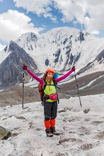 A woman adventurer and climber near a mountain pass on a glacier in a helmet and with a backpack