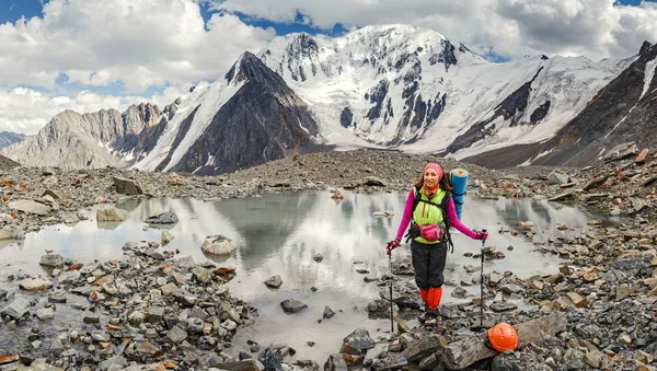 Una mujer aventurera y escaladora cerca de un paso de montaña en un glaciar en un casco y con una mochila — Foto de Stock