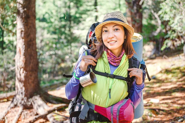 Jovem mulher feliz com mochila caminhando ao longo da trilha pedestre sozinho nas montanhas, o conceito de atividades ao ar livre e aventuras na natureza — Fotografia de Stock
