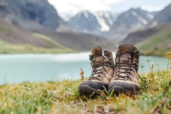 Botas de caminhante em pé na grama perto do lago nas montanhas Altai — Fotografia de Stock