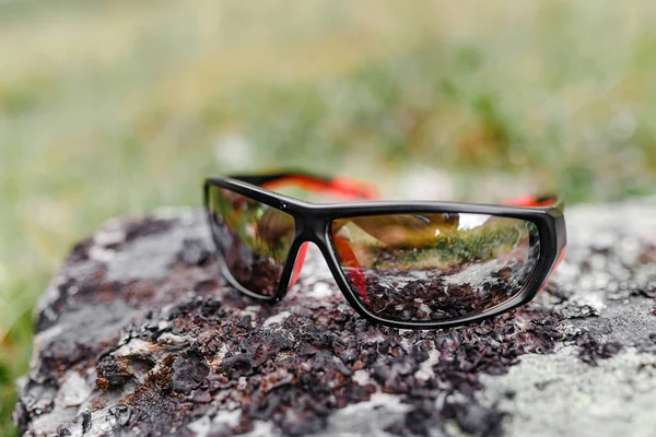 Sportovní mužské sluneční brýle na kámen v horách, cestování koncepce — Stock fotografie