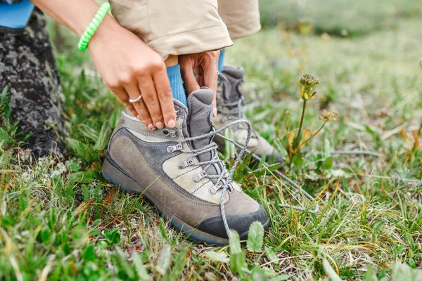 Una mujer turista ata sus cordones en botas de trekking, concepto de calzado al aire libre — Foto de Stock