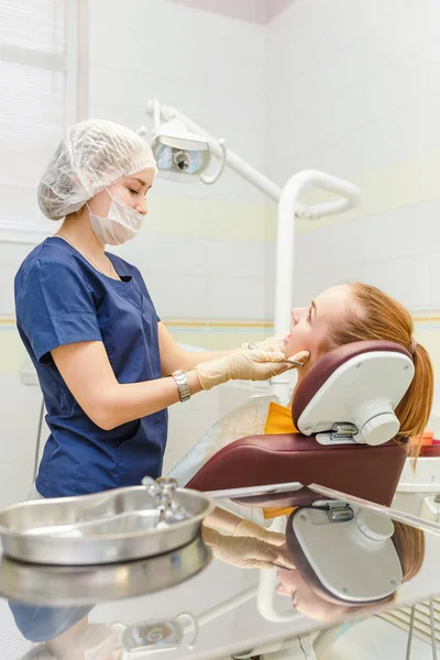 Medico dentista tratta la sua paziente donna in una clinica dentale con attrezzature moderne — Foto Stock
