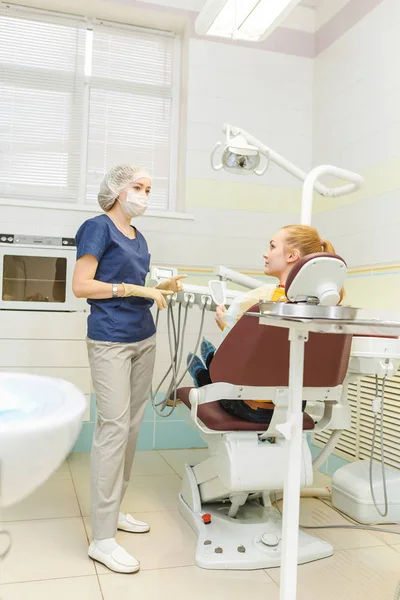 Lekarz dentysta traktuje jej kobieta pacjenta w klinice stomatologicznej z nowoczesnym wyposażeniem — Zdjęcie stockowe