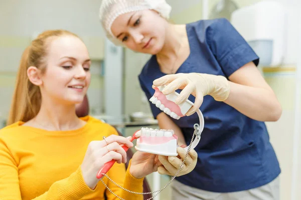 Giovane dentista con modello di mascella e spazzola spiega l'igiene e la salute della bocca e dei denti al suo paziente — Foto Stock