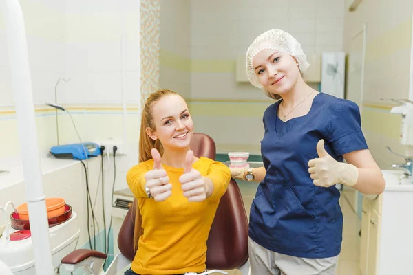 Felice dentista e la sua cliente donna mostrando pollice in su dopo l'esame e l'odontoiatria — Foto Stock
