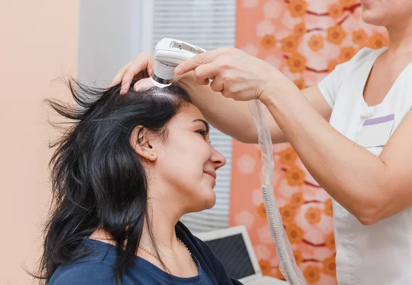 Trichologisk och dermatologisk undersökning av hårbotten och hårsäckar hos en kvinnlig patient i en kosmetologi klinik — Stockfoto