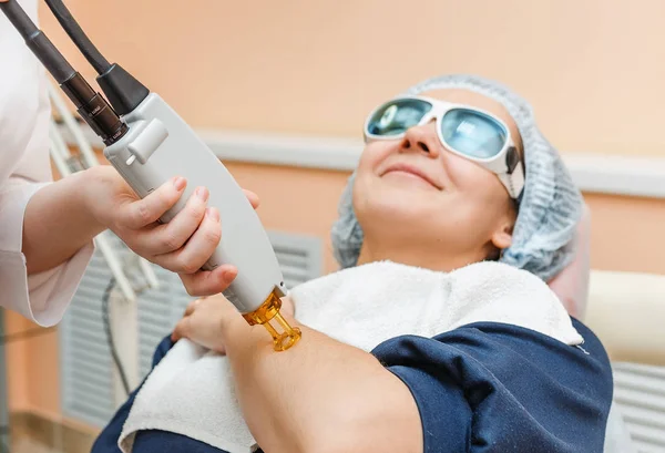 O médico cosmetologista faz o procedimento usando o sistema laser profissional para uma paciente adulta. Depilação a laser e tratamento — Fotografia de Stock