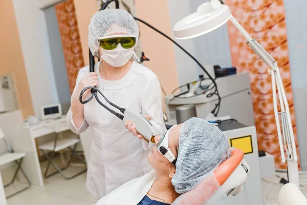 Medico cosmetologo rende la procedura utilizzando il sistema laser professionale per una paziente donna adulta. Epilazione e trattamento laser — Foto Stock