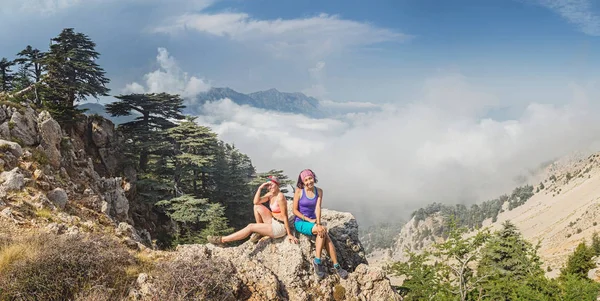 Mujer feliz en la cima de la roca y mirando a la orilla del mar y las montañas de niebla al atardecer en verano . — Foto de Stock