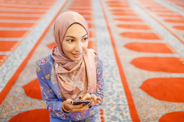 Молодая мусульманка с телефоном в мечети — стоковое фото