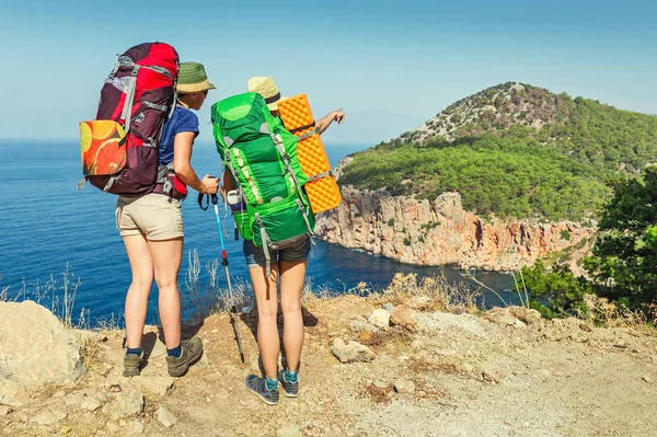 Doi excursioniști cu rucsacuri uitându-se la mare din vârful unui munte — Fotografie, imagine de stoc