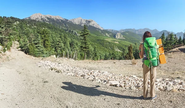 Randonneuse jeune femme avec sac à dos marchant sur un sentier lycien dans la vallée au milieu des montagnes d'été — Photo