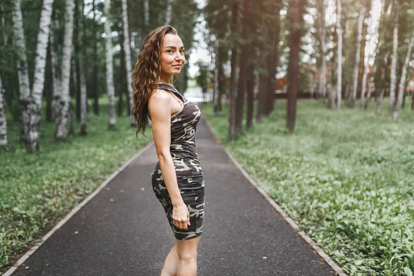 Outdoor portrait of young woman posing outdoors in park in Elegant fitting dress. — Stock Photo, Image