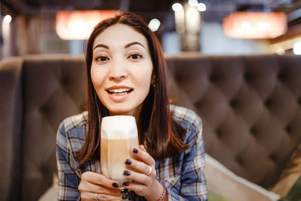 Красивая юная брюнетка восточная женщина сидит в кафе и пьет кофе латте — стоковое фото