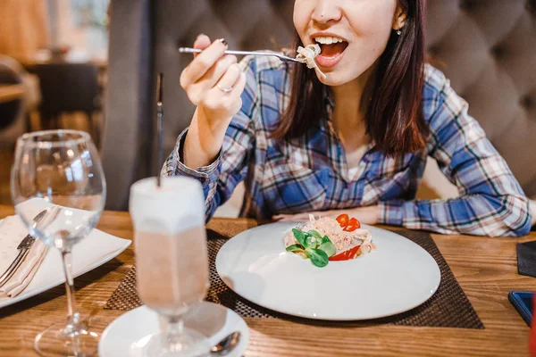 Východní žena jíst špagety těstoviny s vidličkou v luxusní restauraci — Stock fotografie