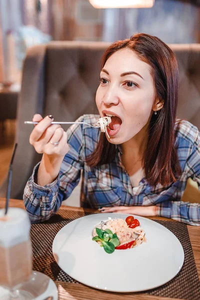 Mujer oriental comiendo pasta de espaguetis con tenedor en un restaurante de lujo —  Fotos de Stock