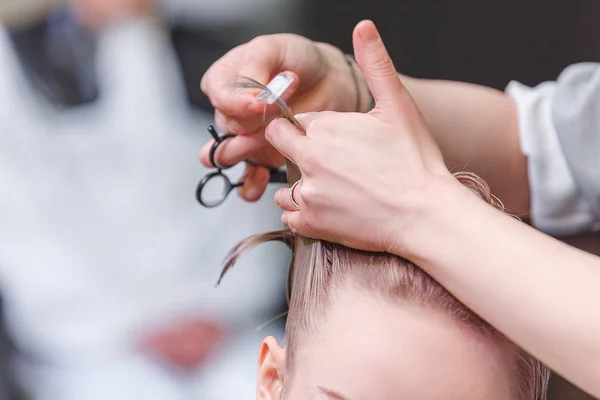 Gros plan d'une coiffeuse qui coupe des cheveux dans un salon de beauté — Photo