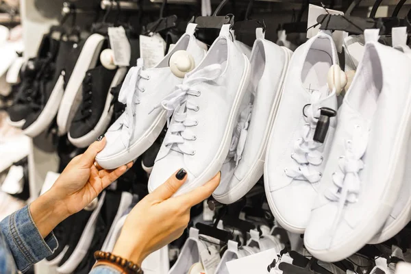 Gelukkig jonge vrouw klant paar sneakers schoenen kiezen en kopen in kleding winkel, ongedwongen winkelen concept — Stockfoto