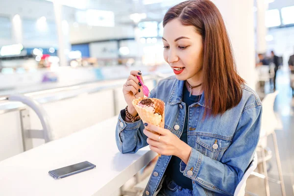 Женщина ест вкусное мороженое в торговом центре после покупок — стоковое фото