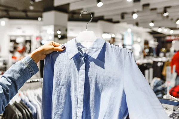 Mulher cliente comprador escolher camisa e outras roupas em uma loja de moda — Fotografia de Stock