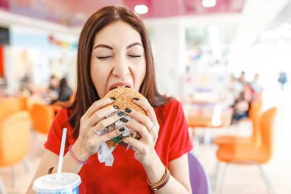 Gezonde jonge vrouw haar hamburger in fastfood Hof bijten — Stockfoto