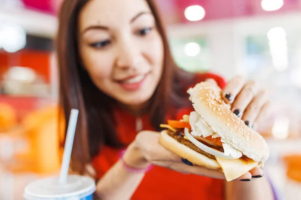 Gezonde jonge vrouw haar hamburger in fastfood Hof bijten — Stockfoto