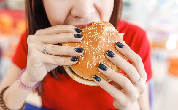 Friska unga kvinnan bita hennes hamburgare i fast foodcourt — Stockfoto