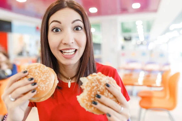 Glückliches Mädchen, das zwei Hamburger als eins isst, Fastfood-Konzept — Stockfoto