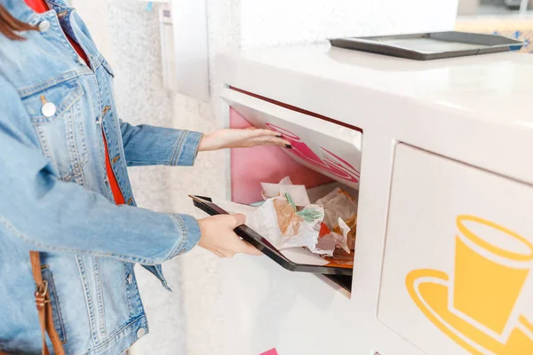 Woman putting garbage and leftovers of the fastfood restaurant to the recycling rubbish bin — Stock Photo, Image